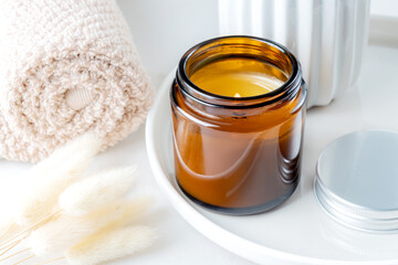 Handmade scented burning candle in a glass with a lagurus plant. Soy wax candles for home decoration.