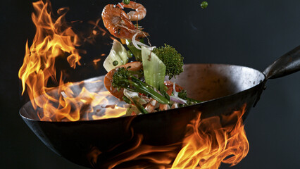 Freeze Motion of Wok Pan with Flying Ingredients in the Air and Fire Flames.