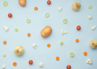 Fresh vegetables on pastel blue background. Onions, carrots, potatoes, cherry tomatoes, hot peppers and cauliflowers. Healthy eating concept.