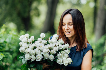 Woman holding flowers big bouquet white flowers roses on dating in city. blooming flowers festive background, pastel and soft bouquet floral card. Mothers day, International Women's Day. © Serenkonata