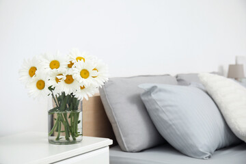 Bouquet of beautiful daisy flowers on table in bedroom, space for text