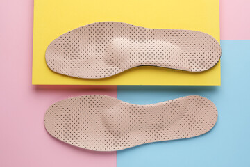 Beige orthopedic insoles on color background, flat lay