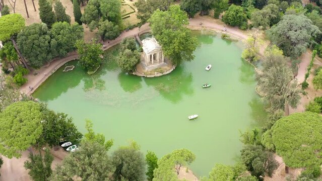 Aerial view of the small lake in Villa Borghese park. This pond is located in Rome, Italy. There are the Temple of Aesculapius and small row boats with people.
