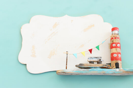 nautical concept with lighthouse driftwood and blank board for copy space over mint blue wooden background