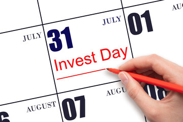Hand drawing red line and writing the text Invest Day on calendar date July 31. Business and...
