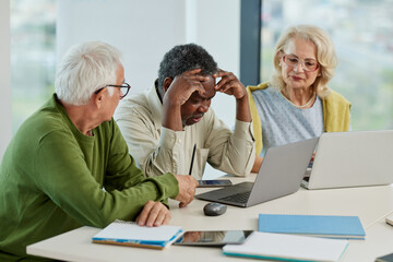 The multicultural senior students having trouble solving a web design problem on a laptop while...