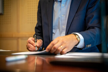 Homme en costard qui signe un document