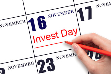 Hand drawing red line and writing the text Invest Day on calendar date November 16. Business and financial concept.