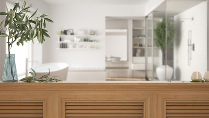 Wooden table top, cabinet, panel or shelf with shutters close up. Olive branch in vase and candles. Blurred background with modern bathroom with bathtub and shower, interior design