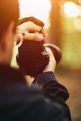 A man holds the mirrorless camera with two hands and the screen is visible. Concept of a hobby...
