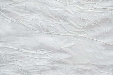 Blank white crumpled and creased paper. White sheet of crumpled paper glued to the wall. Beautiful abstract artistic white empty street poster paper texture pattern