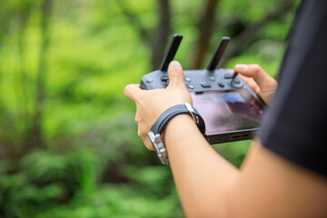 People remote control a flying drone in summer forest