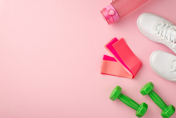 Fitness accessories concept. Top view photo of white sneakers pink bottle of water resistance bands and green dumbbells on isolated pastel pink background with copyspace