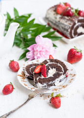 Chocolate roll with strawberries on the holiday table on a sunny morning