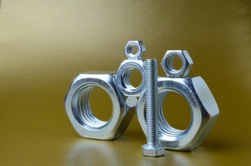 composition of new nuts and bolts of different sizes on a yellow background