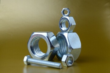 composition of new nuts and bolts of different sizes on a yellow background