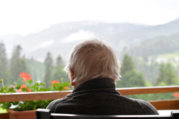 seniorin blickt von balkon in die landschaft