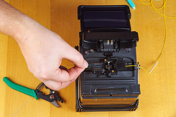 Hand put optical fiber in to splycer.Wooden background