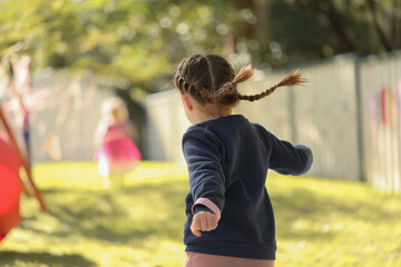 Preschool girl with pigtails jumping, no face visible