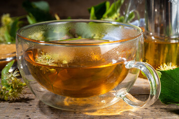 Herbal linden flower tea. linden green tea in glass teapot and tea cup, with fresh linden blossom