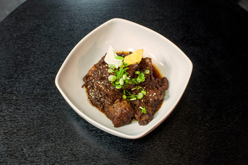 Korean Galbi Jjim, Korean braised short ribs with spring onion on black table background