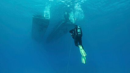  Scuba diver swim towards diving boat in blue water. Mediterranean Sea, Cyprus
