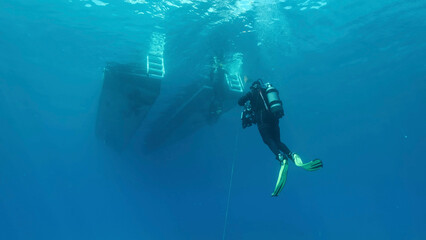  Scuba diver swim towards diving boat in blue water. Mediterranean Sea, Cyprus