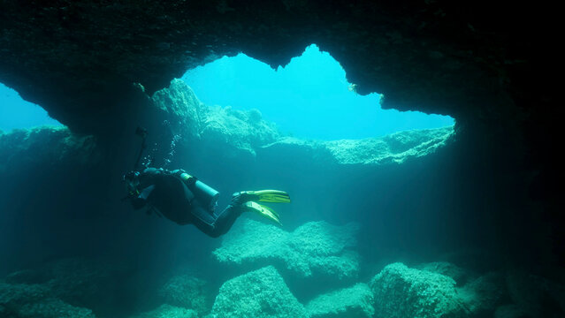 Scuba diver photographer swim in the cave. Cave diving in Mediterranean Sea, Cyprus