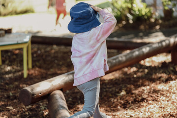 Little preschool girl exploring the garden outdoors at kindergarten