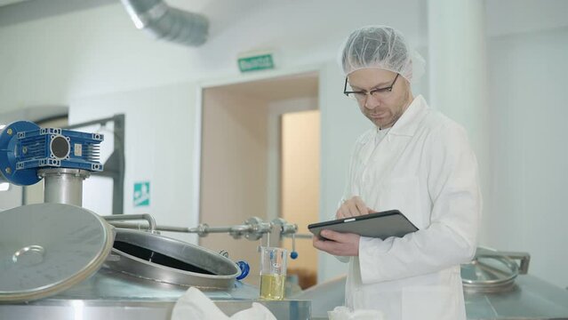 Technician checks beer ingredient sample quality and pours it in tank. Technician assesses the quality of the grain ingredient. Technician is testing the quality of the beer production ingredient.