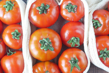 fresh tomato in a reusable shopping bag on table 