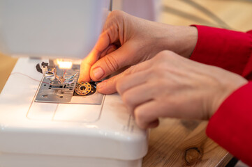 Hands installing spool in sewing machine