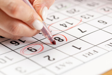 close up on employee woman hand using red pen to writing schedule on 8 day calendar 2022 to make an appointment meeting or manage timetable each day at house for work from home concept