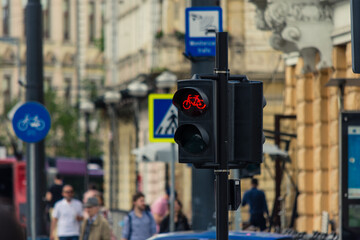 Bike semaphore with red color turned on in an urban area with traffic and people in the background