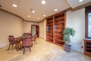 Main area of an office with a round meeting table with wooden furniture with a large wooden shelf for documents with air conditioning and heating