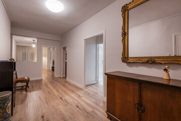 Hallway of a vacation rental home with a beautiful gilt-framed mirror, madra sideboard, and chestnut wood flooring