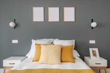 Headboard in a double bedroom with white and yellow cushions, two white and wood nightstands and a solid 18% gray wall