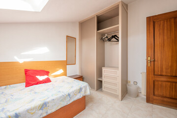 Fototapeta na wymiar Small bedroom with single bed, wardrobe with two sliding doors with drawers and clothes rail