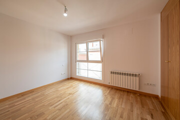 Empty bedroom with white aluminum windows, oak parquet flooring and matching fitted wardrobes