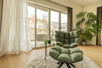 individual green armchair, palm tree in a corner, a nice terrace with aluminum and glass windows