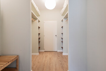 Dressing room of a bedroom with gray painted walls, wooden shelves and parquet floors