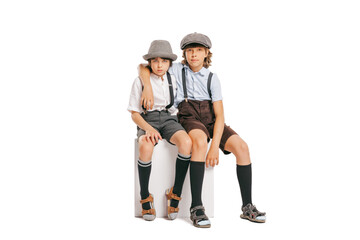 Two school age boys, stylish kids wearing retro clothes posing isolated over white background. Concept of childhood, vintage summer fashion style