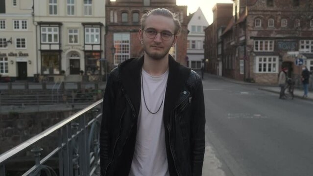Young European Man with Leather Jacket and Glasses walking on Bridge