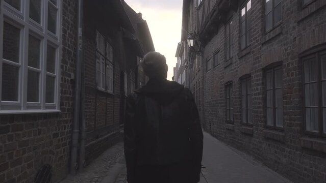 Man in Leather Jacket Walking Through Dark Alley in L&uuml;neburg Oldtown