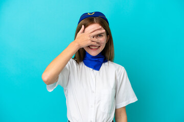 Airplane stewardess English woman isolated on blue background covering eyes by hands and smiling