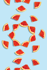 Patterns of slices of juicy grapefruit on a blue background, a beautiful pattern. Top view, full screen. Minimal summer fruits pattern for blog or recipe book.