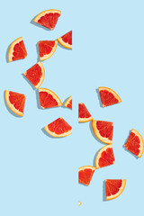 Patterns of slices of juicy grapefruit on a blue background, a beautiful pattern. Top view, full screen. Minimal summer fruits pattern for blog or recipe book.