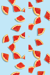 Patterns of slices of juicy grapefruit on a blue background, a beautiful pattern. Top view, full screen. Minimal summer fruits pattern for blog or recipe book.