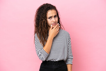Young hispanic woman isolated on pink background having doubts