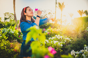 young girl smiling in a beautiful garden enjoying the scent of flowers while feeling relaxed by...